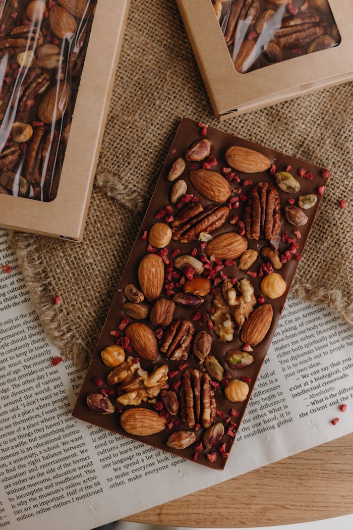 hero-img-02 Handcrafted chocolate bar topped with an assortment of nuts on a rustic burlap background.