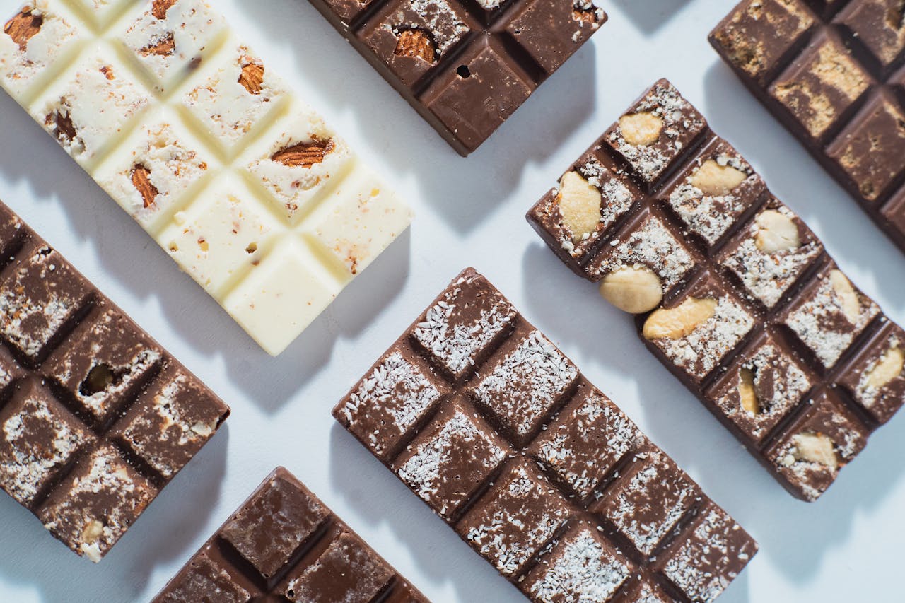 services-01 Flat lay of various chocolate bars featuring almonds and coconut, shot in natural light.