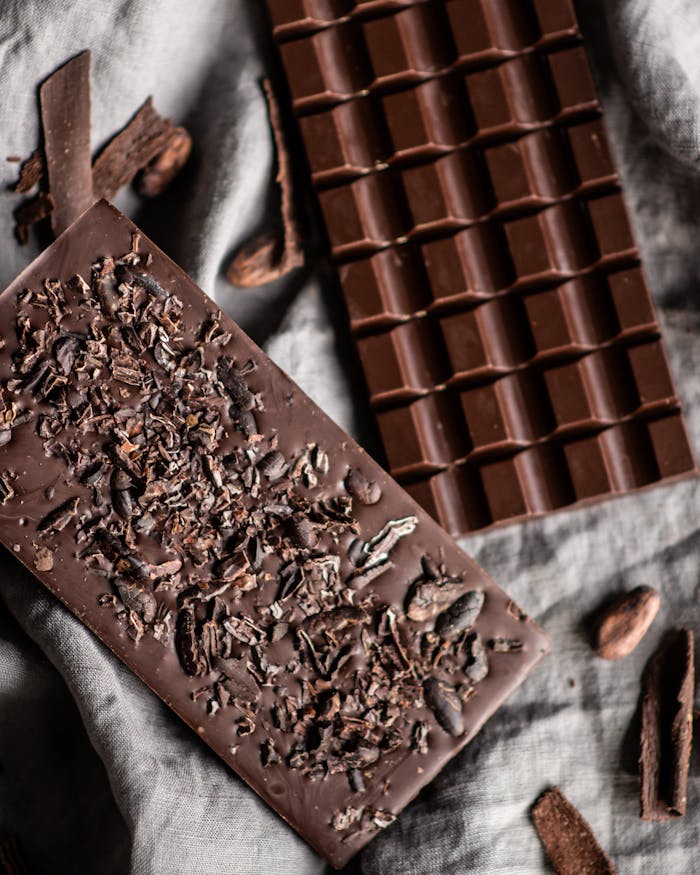 about-01 Tasty dark chocolate bar with cocoa and nut placed on white cloth with crumbs